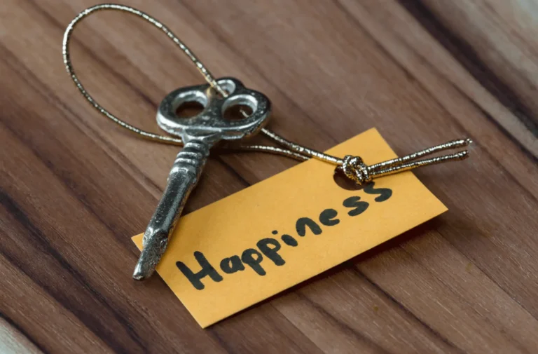 A vintage key attached to a tag marked 'Happiness' on a wooden surface.