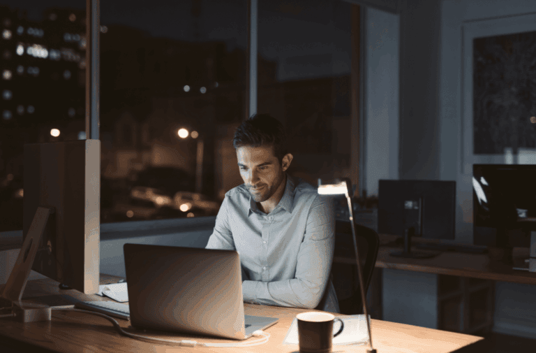 A man working late at night on his laptop in a well-lit office.