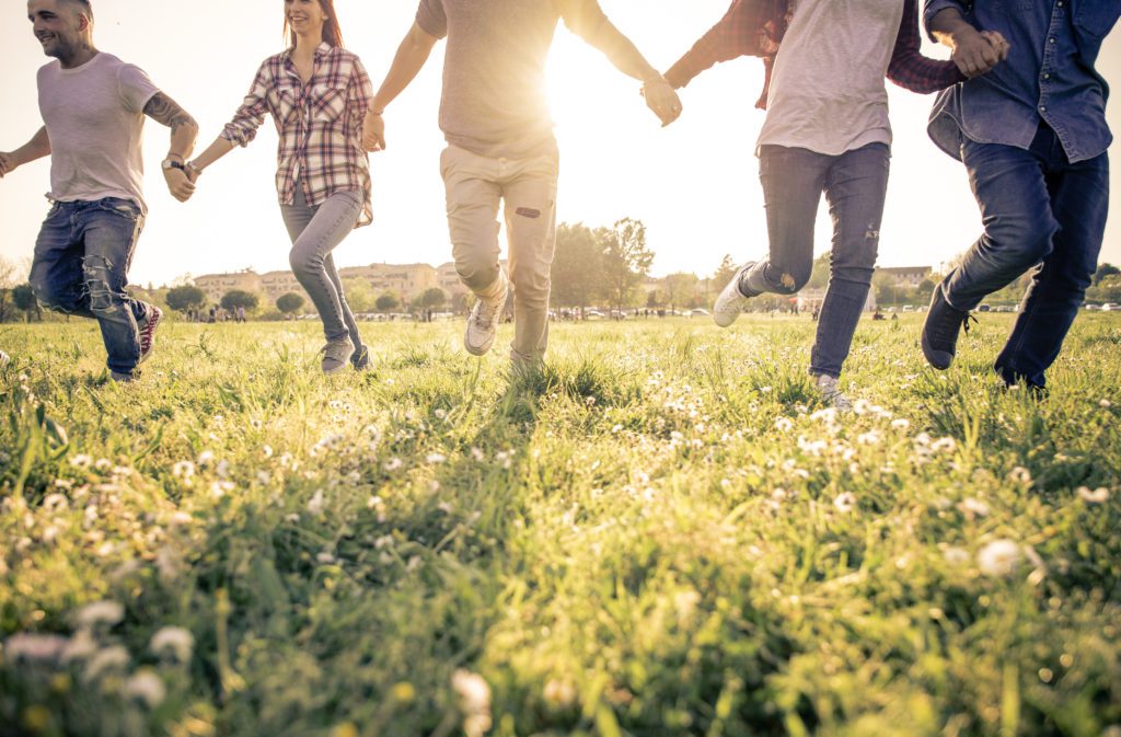 The image is a group of people running together on grass in the sunlight, representing a freedom and happiness