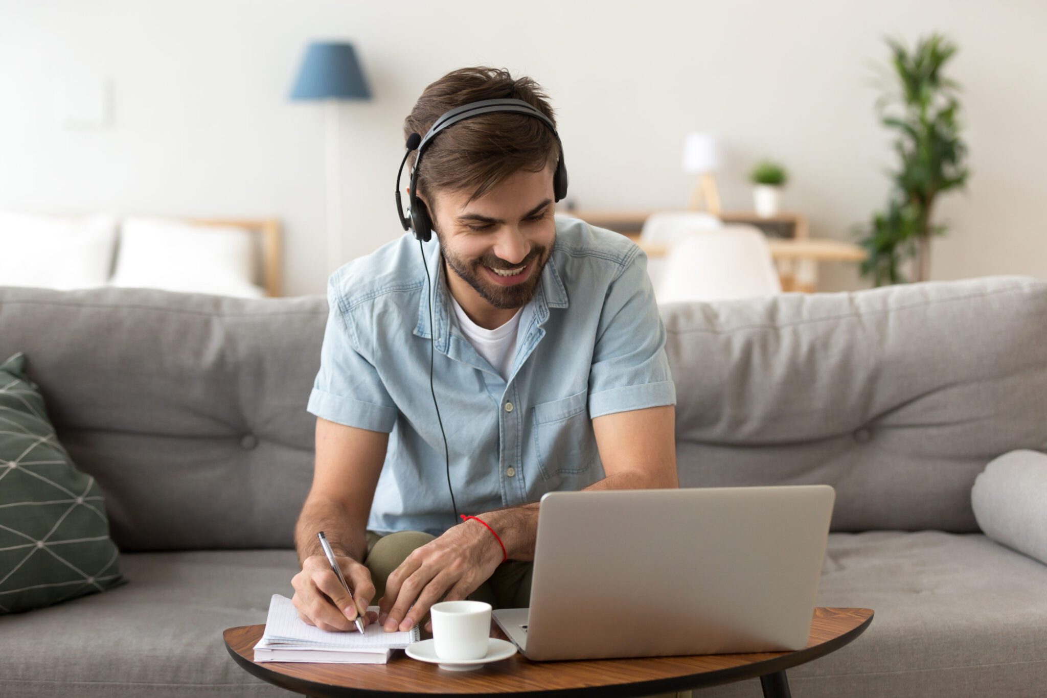 A man undergoing OCD therapy sits on a couch with headphones and a laptop, engaged in therapeutic activities.