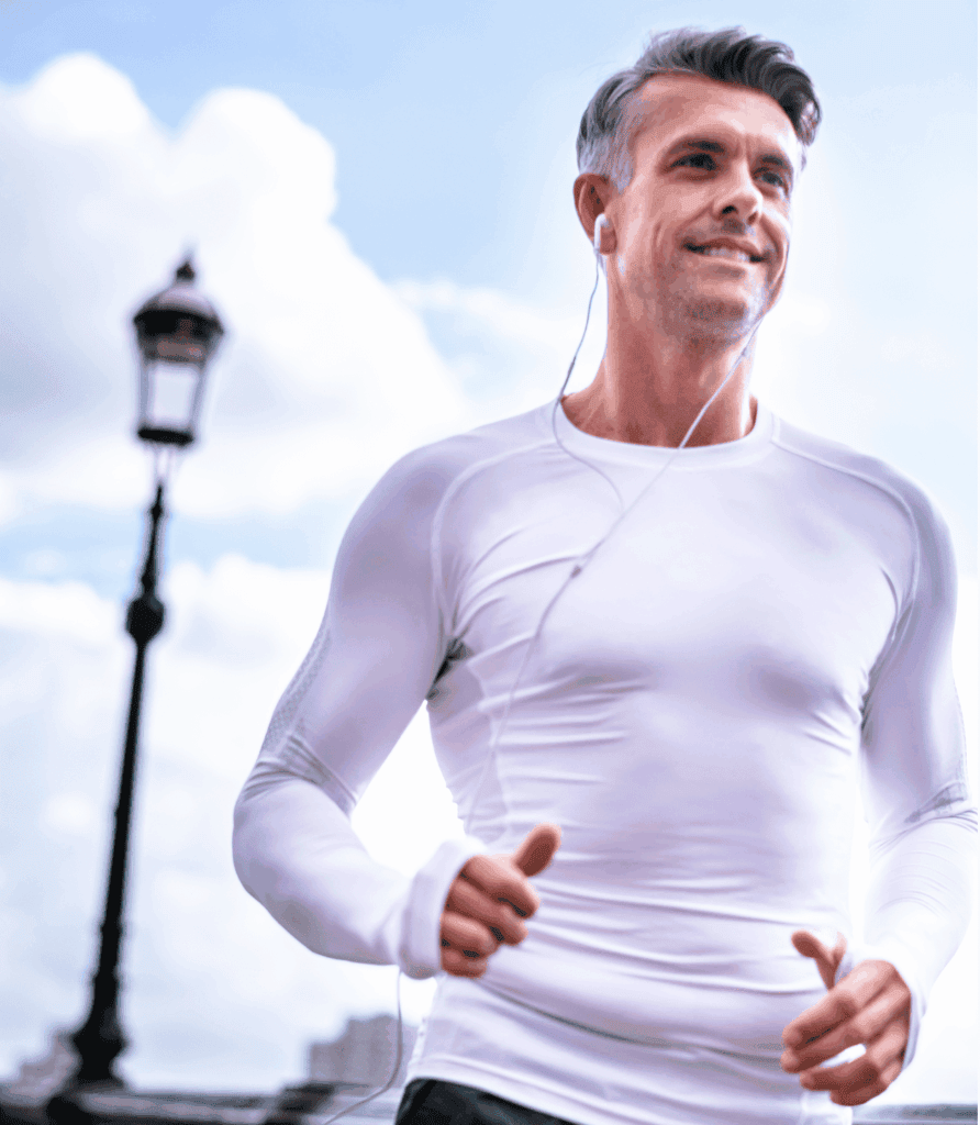 A man jogging outdoors wearing a white long-sleeve top and earphones.