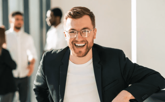 A cheerful male portrait in a modern office setting, showcasing a friendly demeanor.