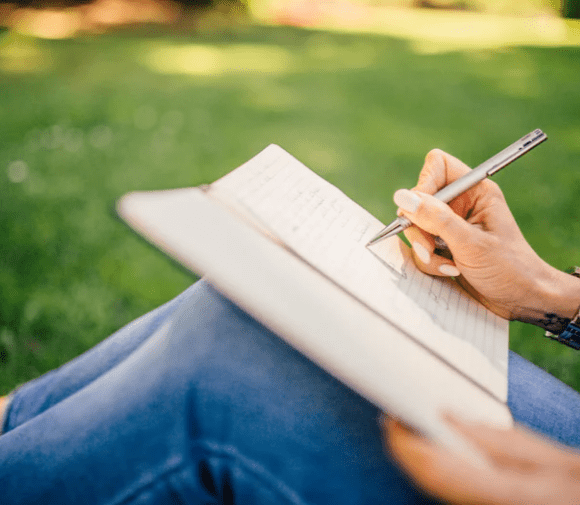 woman setting on the ground writing notes
