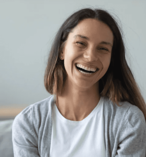 A woman with long hair smiling warmly, radiating positivity.