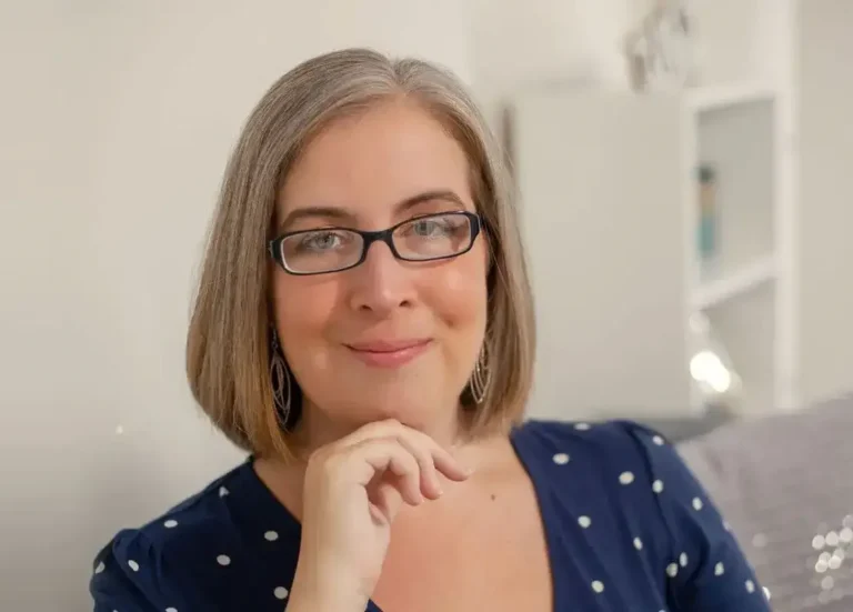 Close-up portrait of Hannah Paskin smiling while resting her chin on her hand.