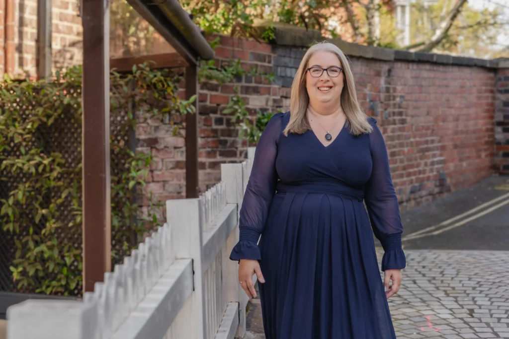 Outdoor portrait of a Hannah Paskin in a navy dress with a relaxed smile.